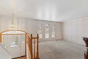 Carpeted entrance foyer featuring plenty of natural light and a chandelier