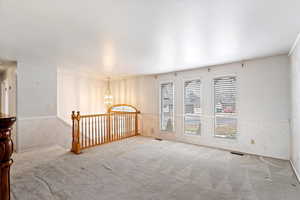 Carpeted empty room featuring an inviting chandelier