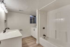 Bathroom featuring shower / bath combination, vanity, wood-type flooring, and a textured ceiling