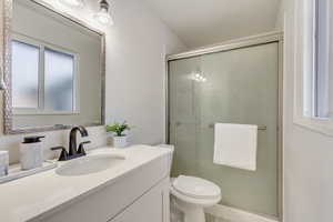 Bathroom with vanity, toilet, and a shower with door