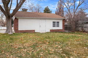 Garage featuring a lawn and mature trees