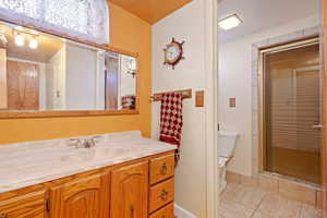 Bathroom featuring tile patterned flooring, vanity, toilet, and a shower with door