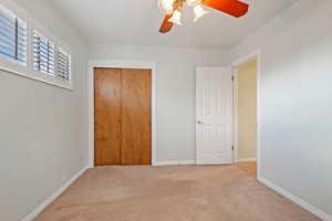 Unfurnished bedroom with ceiling fan, light colored carpet, and a closet