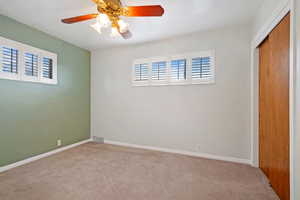 Unfurnished bedroom with ceiling fan, a closet, and light colored carpet