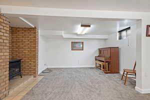 Basement featuring a wood stove and light carpet