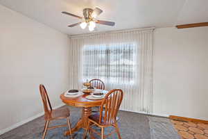 Carpeted dining room featuring ceiling fan