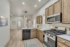 Kitchen with sink, hanging light fixtures, light hardwood / wood-style flooring, appliances with stainless steel finishes, and kitchen peninsula