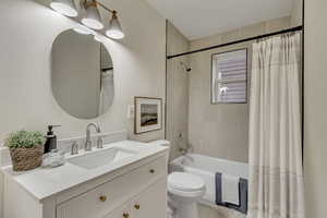 Full bathroom featuring vanity, toilet, and shower / bathtub combination with curtain