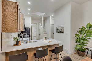 Kitchen featuring a kitchen bar, kitchen peninsula, sink, and light wood-type flooring