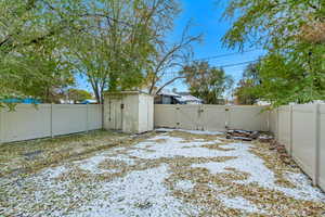 Yard layered in snow with a shed