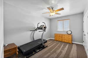 Workout area with ceiling fan and dark carpet