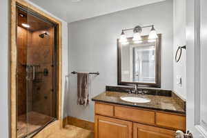 Bathroom featuring tile patterned flooring, vanity, a shower with door, and a textured ceiling