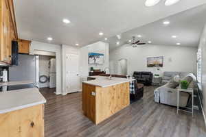 Kitchen featuring sink, dark wood-type flooring, white refrigerator, an island with sink, and lofted ceiling