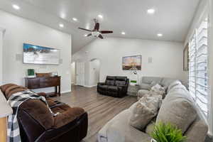 Living room featuring ceiling fan, wood-type flooring, and vaulted ceiling