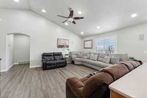 Living room with light hardwood / wood-style floors, high vaulted ceiling, and ceiling fan