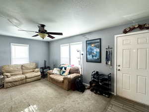 Living room with a textured ceiling, hardwood / wood-style flooring, a wealth of natural light, and ceiling fan