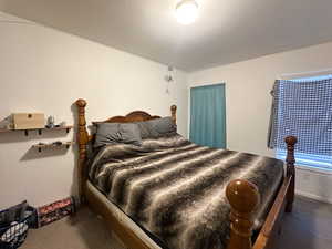 Bedroom featuring dark colored carpet and a textured ceiling