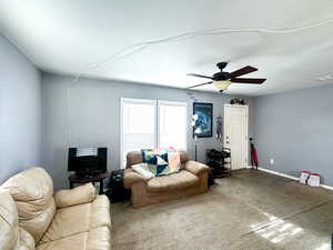 Living room with carpet, ceiling fan, and a textured ceiling