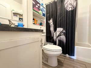 Full bathroom with toilet, hardwood / wood-style floors, vanity, and shower / tub combo with curtain