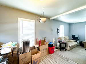 Interior space featuring beam ceiling, light colored carpet, and a textured ceiling