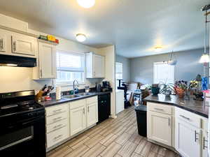 Kitchen featuring hanging light fixtures, black appliances, a textured ceiling, and sink