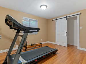 Exercise room featuring a barn door and light wood-type flooring