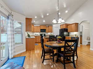 Dining space featuring light wood-type flooring, high vaulted ceiling, and an inviting chandelier