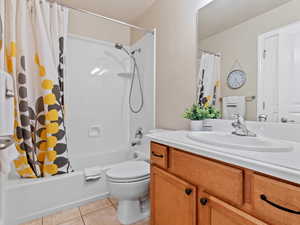 Full bathroom with tile patterned flooring, vanity, toilet, and shower / bath combo with shower curtain