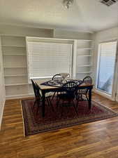 Dining space featuring built in shelves, dark hardwood / wood-style flooring, and a textured ceiling