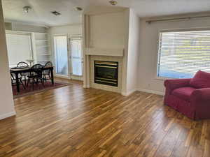 Living room featuring dark hardwood / wood-style floors, a tiled fireplace, a textured ceiling, and a wealth of natural light