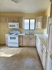 Kitchen featuring sink, light brown cabinets, and white appliances