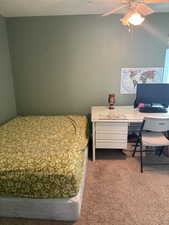 Bedroom with ceiling fan, a textured ceiling, and carpet flooring