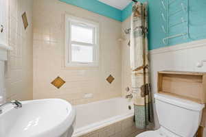 Full bathroom featuring toilet, sink, and shower / tub combo with curtain