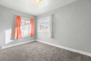 Empty room with carpet flooring and a textured ceiling