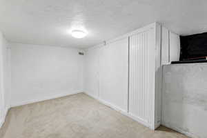 Interior space with a textured ceiling and light carpet