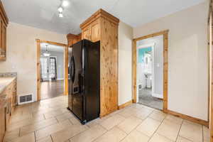 Kitchen featuring french doors, sink, hanging light fixtures, a textured ceiling, and black fridge with ice dispenser