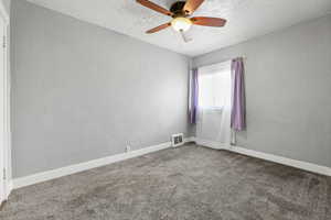 Carpeted empty room featuring a textured ceiling and ceiling fan