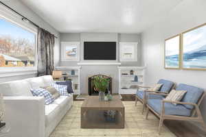 Living room with a wealth of natural light, light hardwood / wood-style floors, and a textured ceiling