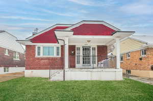 View of front of house with a front yard and a porch