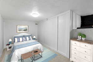 Bedroom with a textured ceiling and light carpet