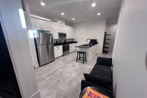 Kitchen with a kitchen breakfast bar, sink, white cabinets, and appliances with stainless steel finishes