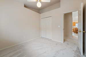 Unfurnished bedroom featuring ceiling fan, light carpet, and a closet