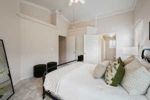 Carpeted bedroom featuring ceiling fan, ornamental molding, ensuite bathroom, and a high ceiling