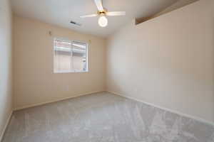 Carpeted empty room with ceiling fan and vaulted ceiling