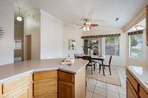 Kitchen with lofted ceiling, crown molding, hanging light fixtures, ceiling fan, and light tile patterned flooring