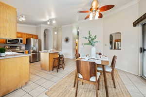 Tiled dining space featuring a textured ceiling, ceiling fan, ornamental molding, and rail lighting