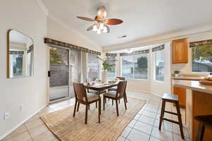 Dining room with a textured ceiling, light tile patterned flooring, a healthy amount of sunlight, and lofted ceiling