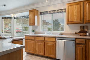 Kitchen with stainless steel dishwasher, light tile patterned floors, sink, and a wealth of natural light