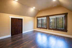 Bonus room with dark wood-type flooring and lofted ceiling