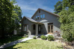 Back of house with stucco siding and a lawn